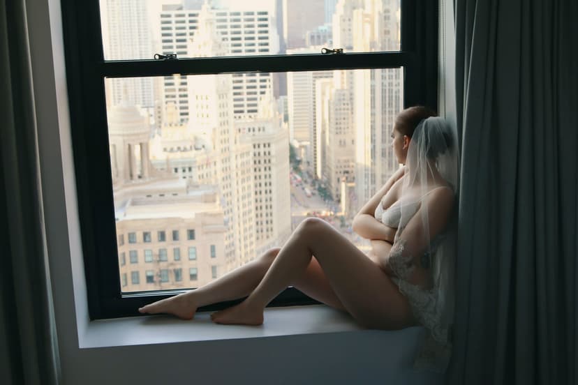 Boudoir bridal portrait by a large window overlooking skyline; remove blemishes and redness, enhance delicate highlights