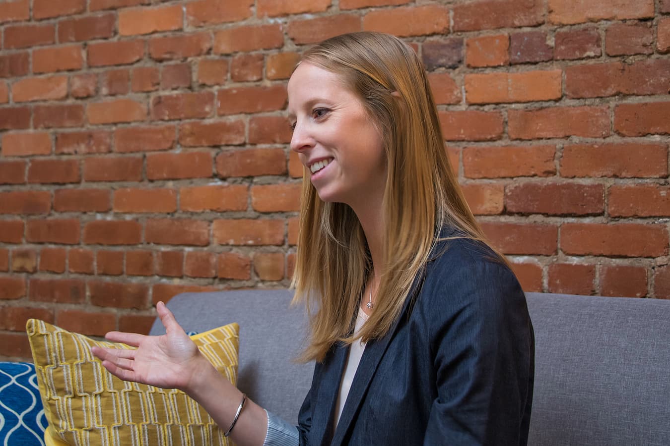 Office lifestyle headshot of a woman with long light brown hair; background cleanup, color correction, skin and facial retouching