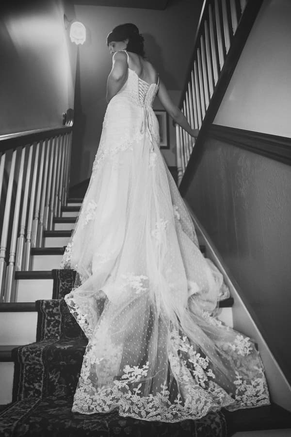 Bride walking up an indoor staircase, dress detail enhancement on lace train, color correction, and background cleanup for a tidy hallway