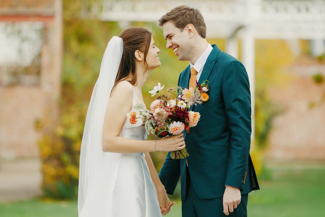 Bride and groom smiling nose-to-nose in a garden, color correction and gentle color grading, skin retouching with natural texture