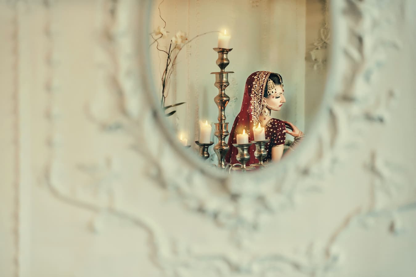Bride in traditional attire seen in a mirror with candles, color correction for a moody look, background cleanup, and skin retouching kept natural
