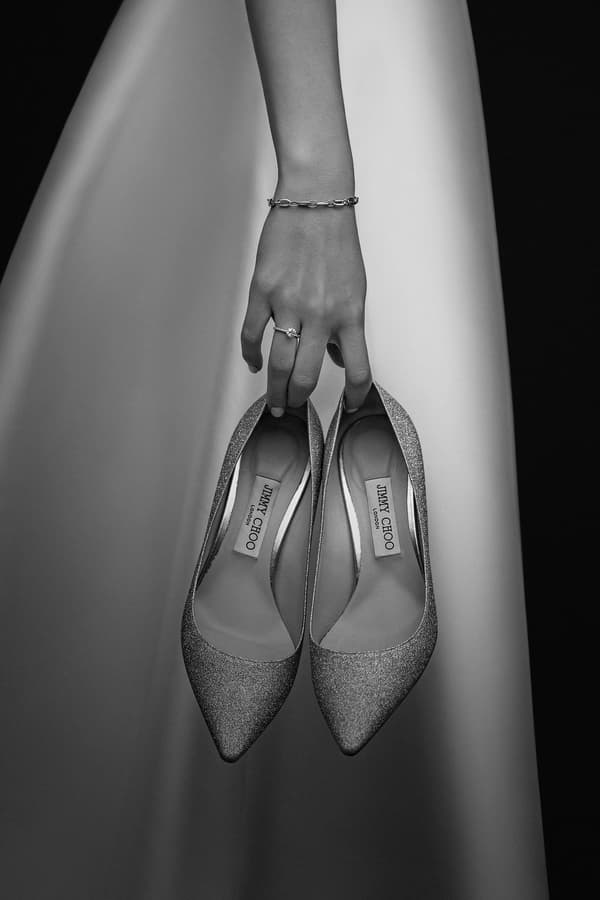 Bride holding Jimmy Choo wedding shoes with engagement ring and bracelet