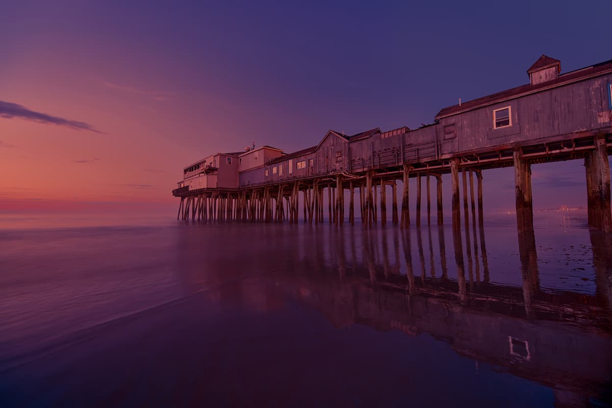Seascape at sunset with calm water and pier, refined color and light, sky color enhancement for depth