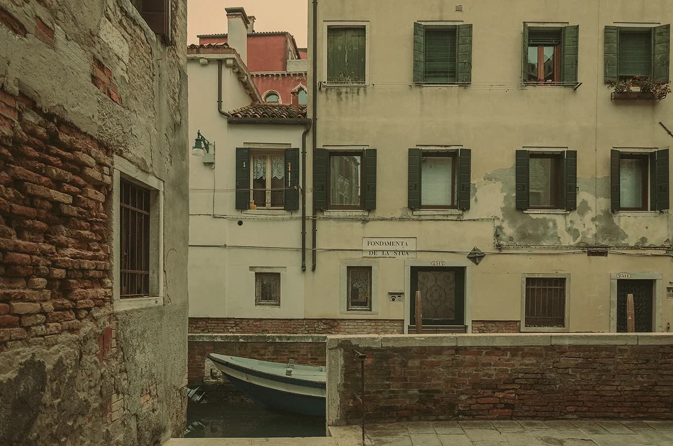 Quiet Venice canal with a small boat and aged facades; background cleanup, color correction, and artistic grading for a soft editorial travel look